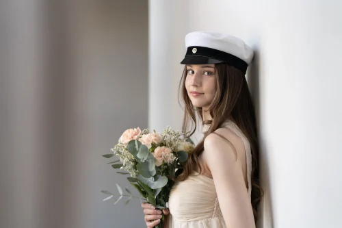 Ylioppilas kukkakimppu kädessään vaaleiden pylväiden vieressä.